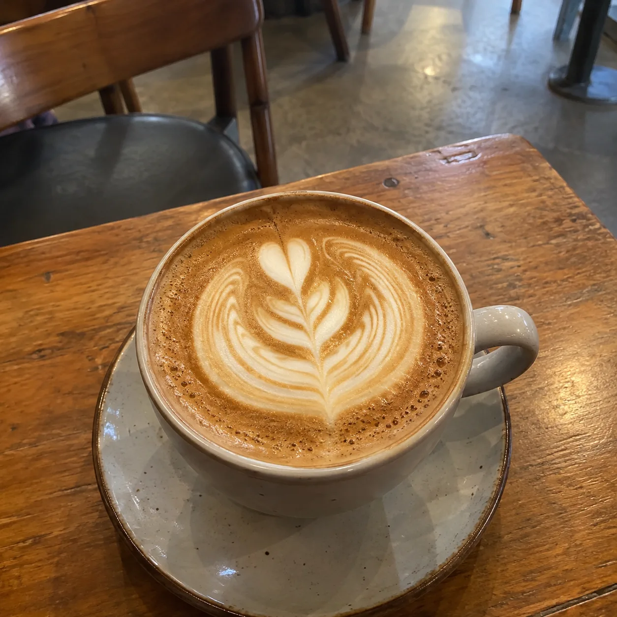 Flat phone photo of a latte before Feedtray enhancement showing the coffee shop Instagram photo problem
